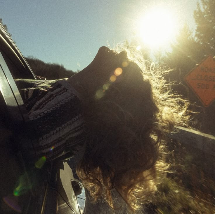 the sun shines brightly on a woman's head from inside a car window