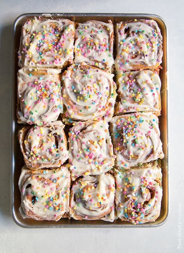 sprinkle covered doughnuts in a pan on a white table top, ready to be eaten