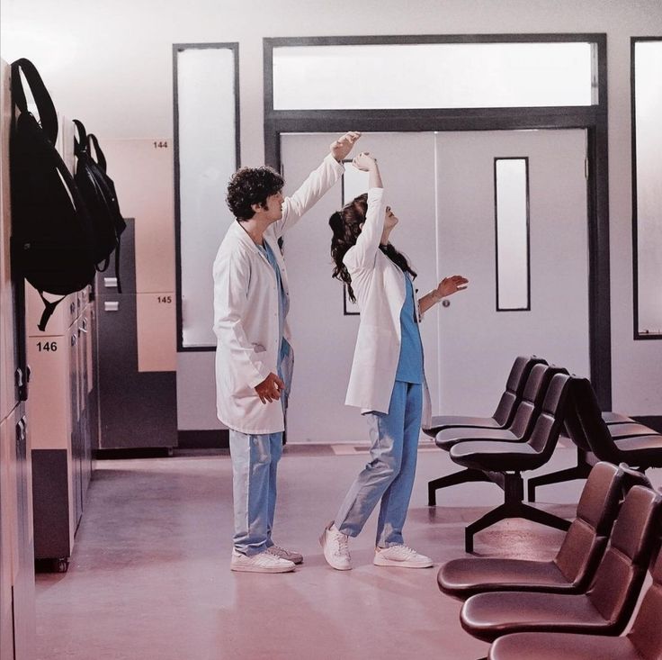 two people standing in an empty room with chairs and one person reaching up for something