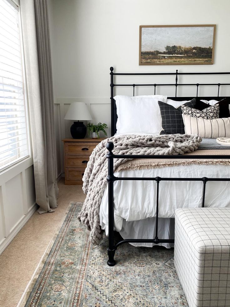 a bed with white sheets and pillows on top of it next to a window in a bedroom