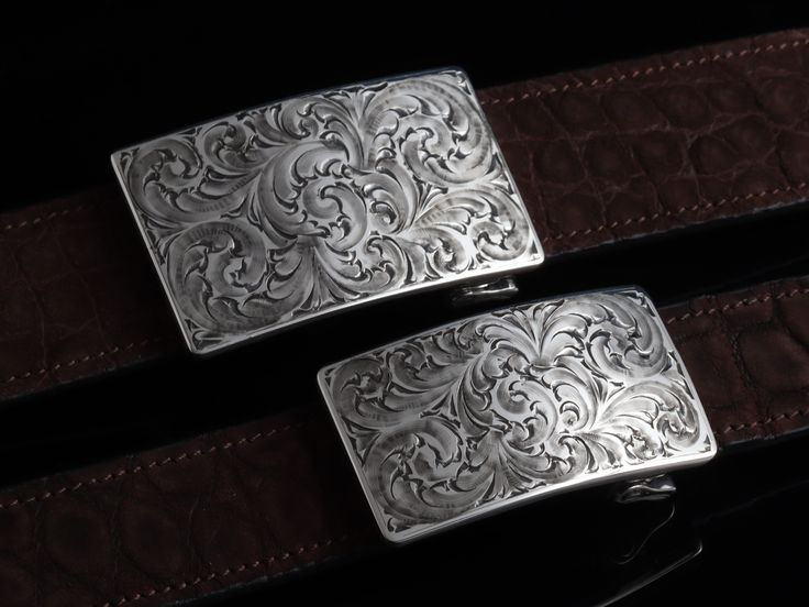 One of our most popular buckles, this understated piece by Comstock Heritage is perfect for those just starting their buckle collections, or for more formal occasions. It’s made from heavy-gauge, hand-engraved Sterling silver, and its rectangular face is adorned with beautiful, delicate scrollwork. This buckle can be paired easily blue jeans or be worn with dressier slacks. This buckle comes in two sizes as well. First smaller size measures approx. 1 5/8" x 2 5/8" and fits all 1.25" belt traps S Luxury Formal Belts With Silver Buckle, Luxury Formal Belt With Silver Buckle, Classic Formal Engraved Belt, Classic Formal Belts With Engraved Details, Classic Formal Belt With Engraved Details, Formal Engraved Belt Buckles, Classic Engraved Belts For Formal Occasions, Luxury Engraved Silver Belt Buckles, Western Engraved Belt Buckles For Formal Wear