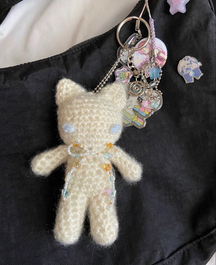 a crocheted teddy bear keychain is sitting on a black piece of fabric