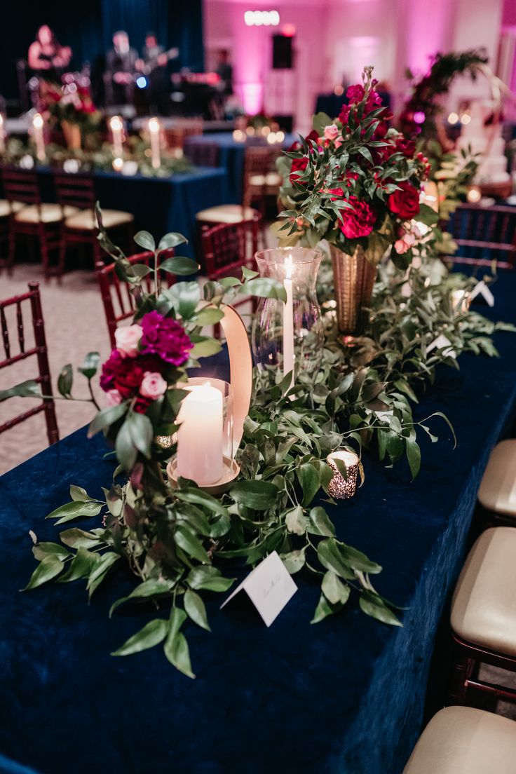 the table is set with candles, flowers and greenery