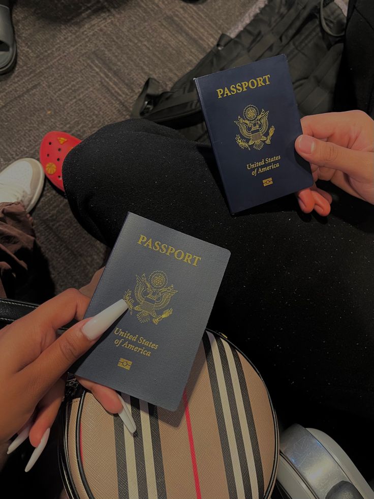 two people sitting on the floor with their luggage and one has a passport in front of them