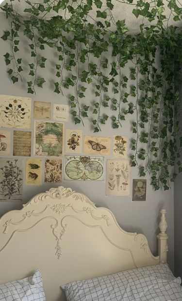 a white bed topped with lots of green plants next to a wall covered in pictures