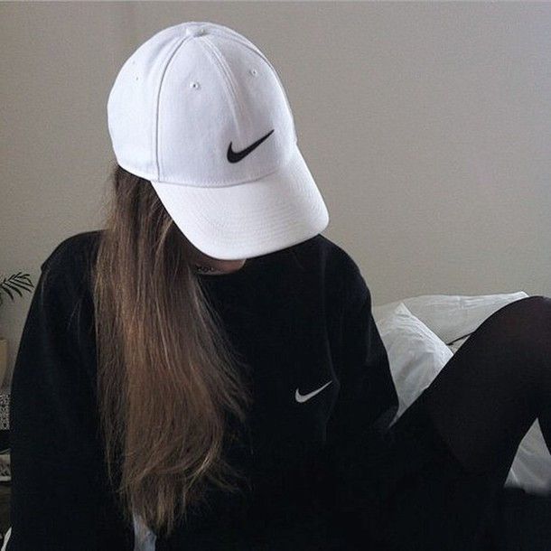 a woman with long hair wearing a nike hat