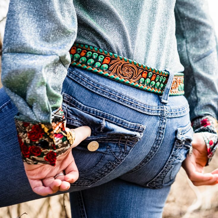 two people holding hands while wearing jeans and belted belts with beads on them,