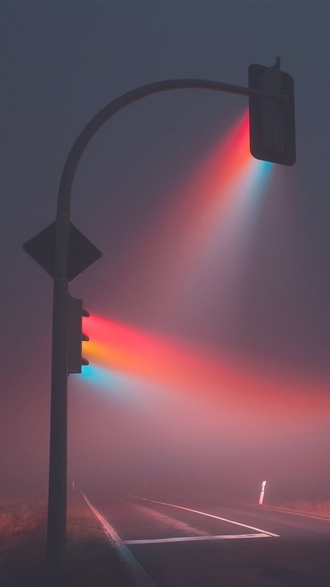 a traffic light on a foggy day with the sun shining brightly through the clouds