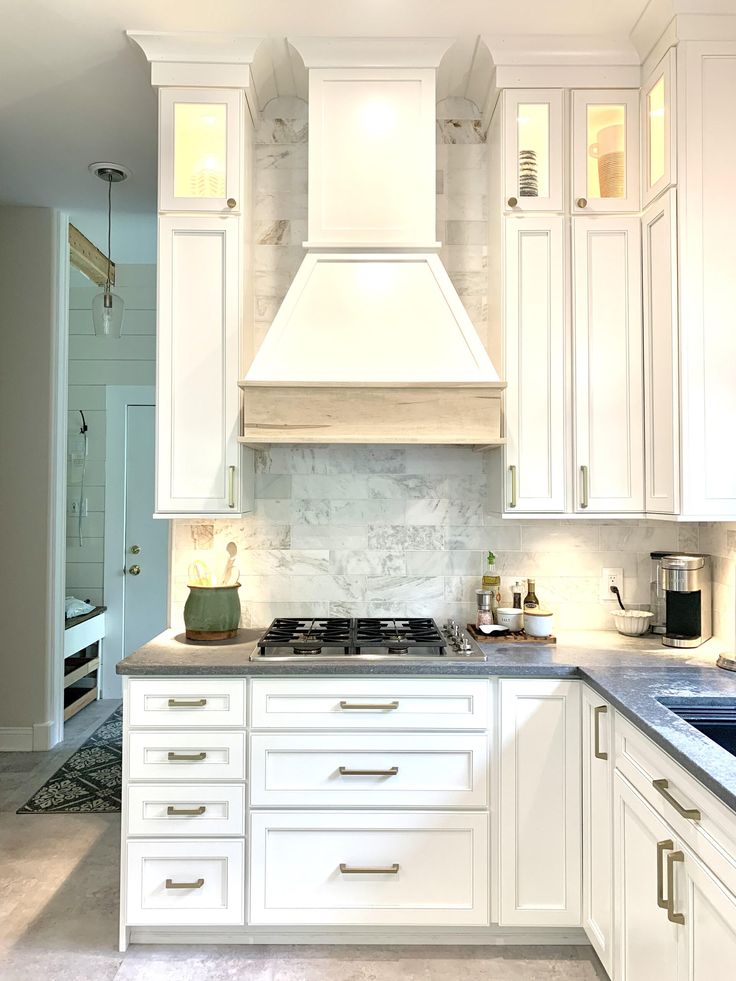 a kitchen with white cabinets and marble counter tops is seen in this image from the front view