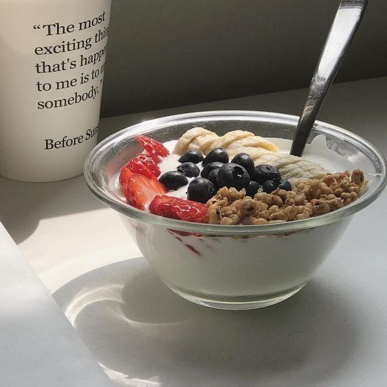 a bowl of cereal with fruit and yogurt next to a cup of coffee