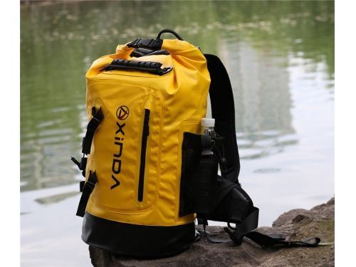 a yellow backpack sitting on top of a rock near water