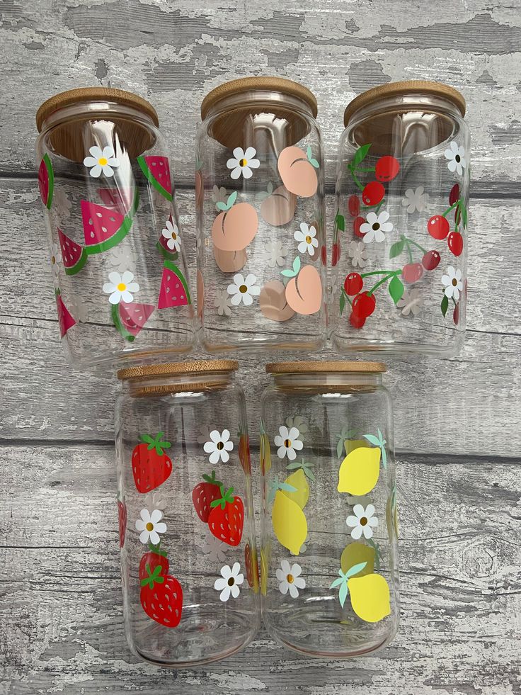 four glass jars with strawberries, lemons, and strawberrys painted on them