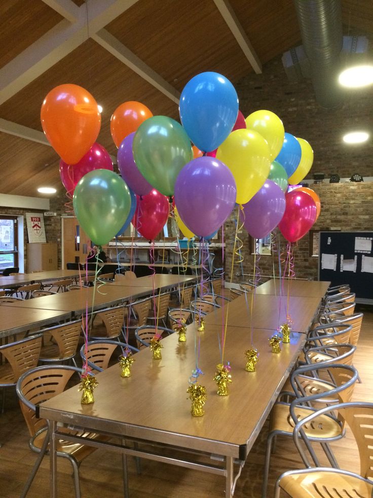 tables and chairs with balloons on them in a room