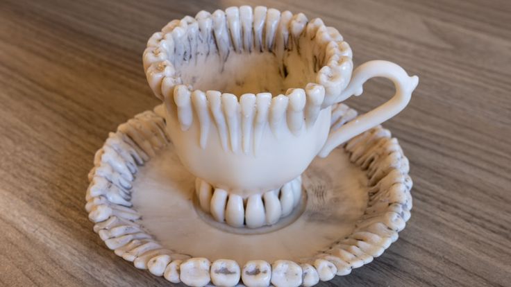 a white cup and saucer sitting on top of a wooden table next to each other