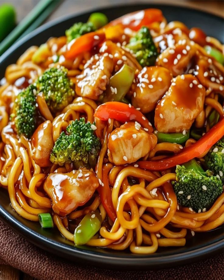 a black plate topped with noodles and chicken