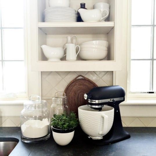 a kitchen counter topped with white dishes and appliances