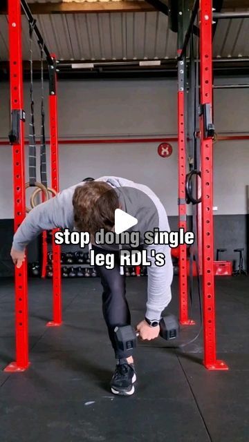 a man squats down in the middle of a crossfit gym with his hands behind his head