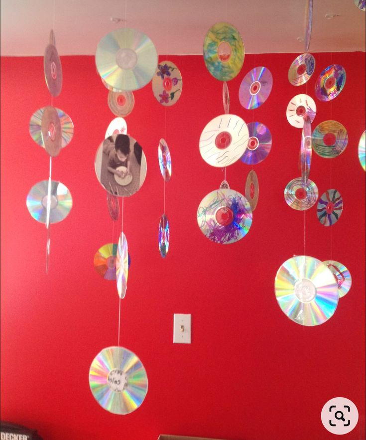 a red wall with cds hanging from it's sides and a dog in the middle