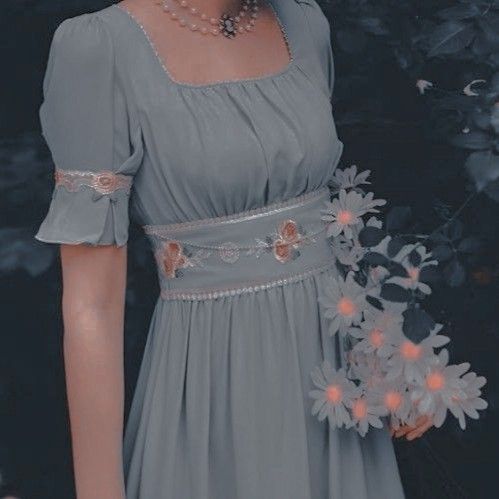 a woman in a gray dress holding a bouquet of flowers and wearing pearls on her head