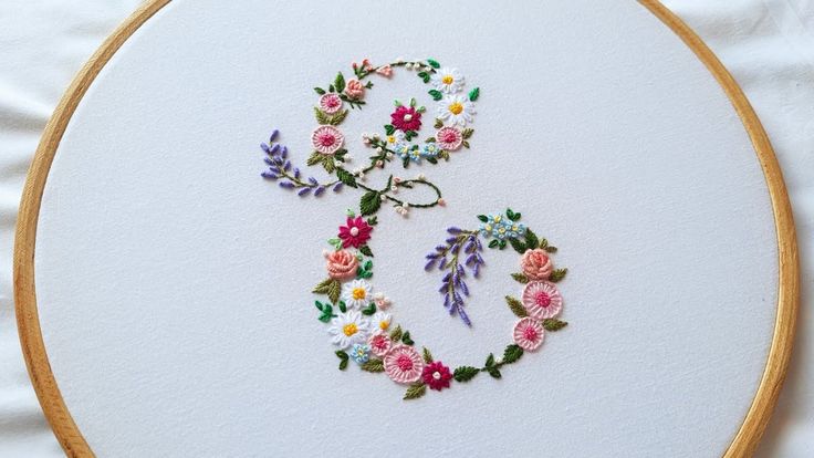 a cross stitch pattern with flowers and the letter s in it's center on a white background