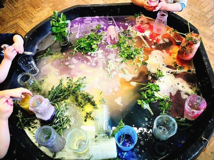 several people are sitting at a table with drinks and plants in the middle of it