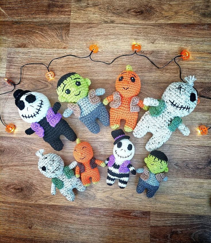 a group of crocheted stuffed animals sitting on top of a wooden floor next to string lights