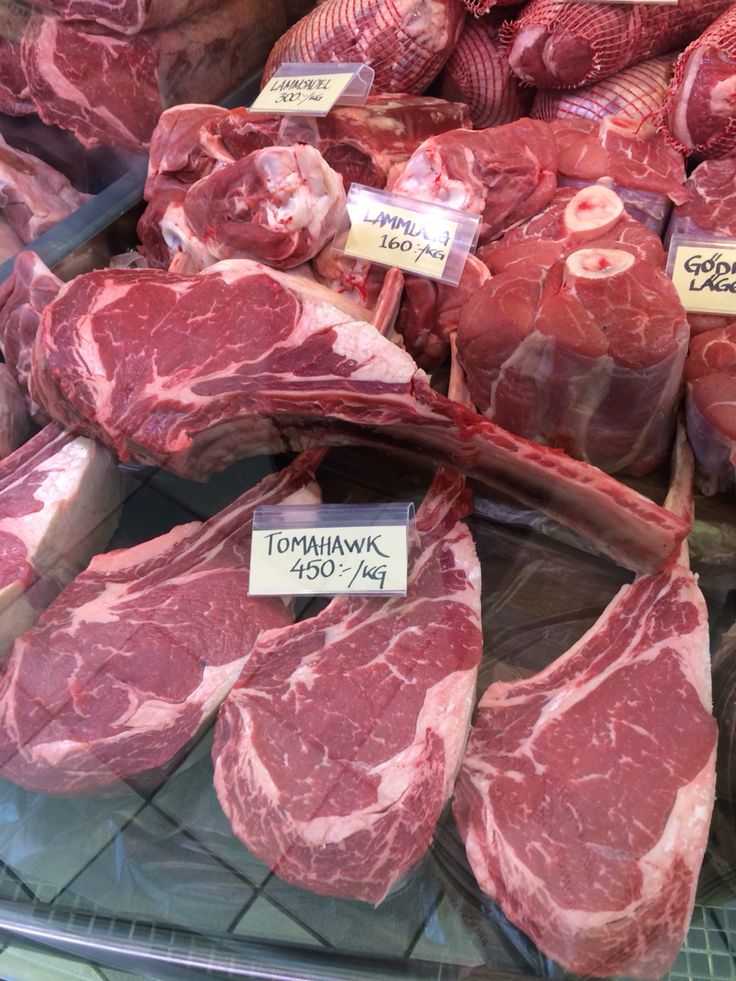 various cuts of meat on display at a butcher's shop with price tags attached to them