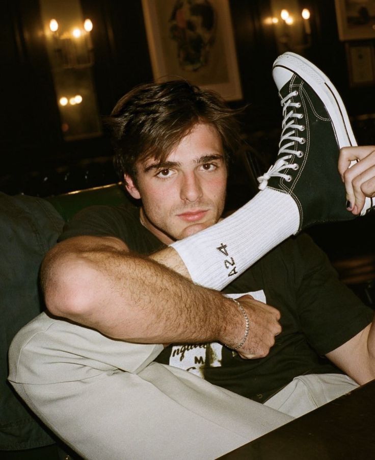 a man sitting on top of a couch holding up his shoe