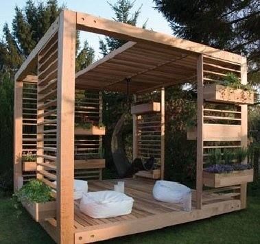 a wooden gazebo with white pillows on it in the middle of a grassy area