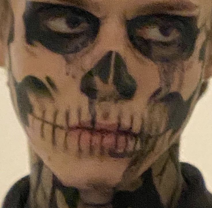 a man with makeup on his face is dressed as a skeleton