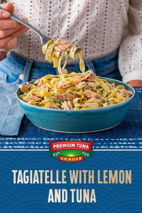 a person holding a spoon full of pasta with lemon and tuna in it on a blue table cloth