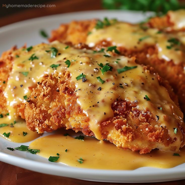 two pieces of chicken covered in gravy on a plate with parmesan cheese