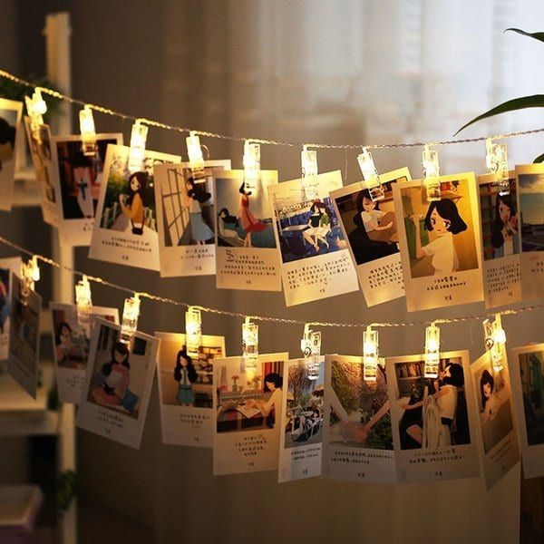 some pictures are hanging on a string with lights