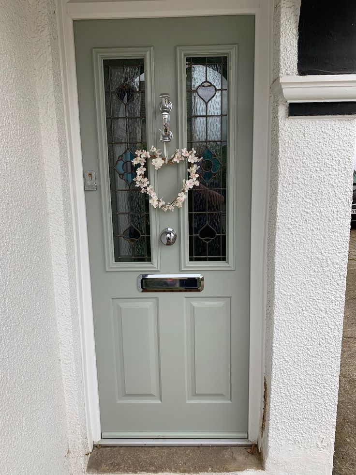 a green door with two wreaths hanging on it's side and glass windows