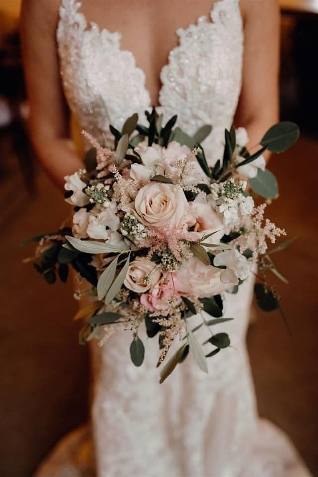 a bridal holding a bouquet of flowers and greenery