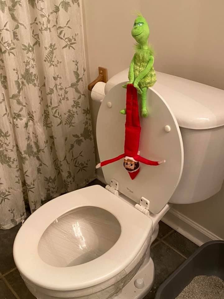 a white toilet sitting in a bathroom next to a shower curtain with a green stuffed animal on top of it