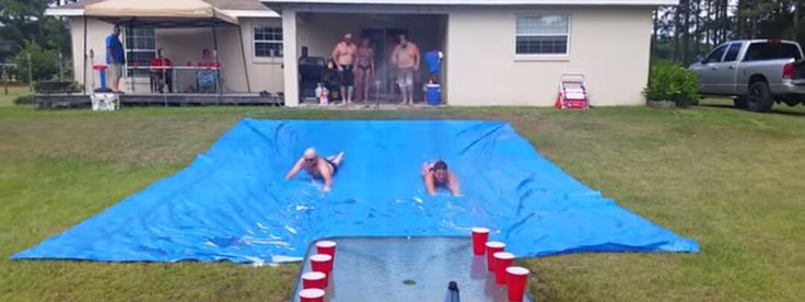 two people are swimming in a pool with a blue tarp covering it and red buoys