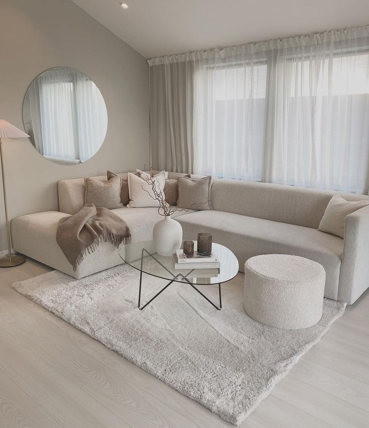 a living room filled with furniture and a round mirror on the wall over a coffee table