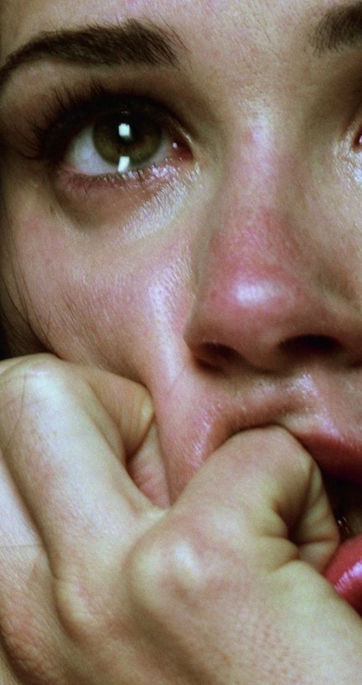 a close up of a person holding their hand to her face and looking at the camera