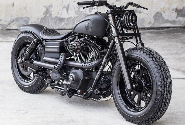 a black motorcycle parked in front of a concrete wall with no one around the bike