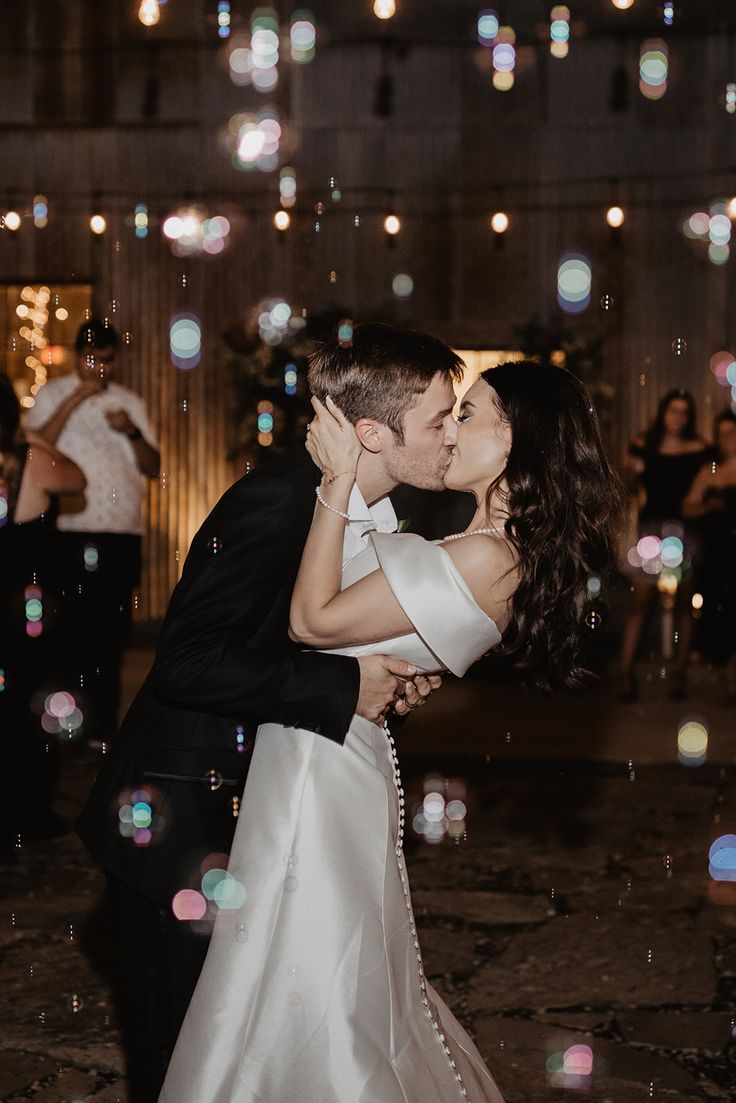 a bride and groom kissing in front of bubbles on the dance floor at their wedding