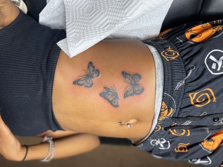 a woman's stomach with butterflies tattooed on her belly and the bottom part of her body