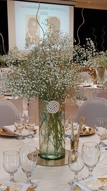 a vase filled with baby's breath sitting on top of a white table cloth