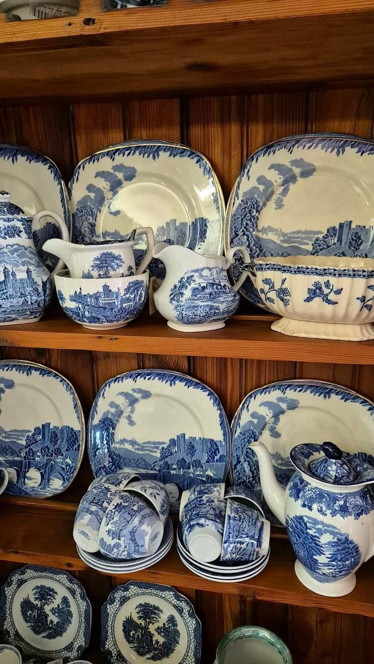 blue and white china is on display in a store shelf with wooden shelves behind it