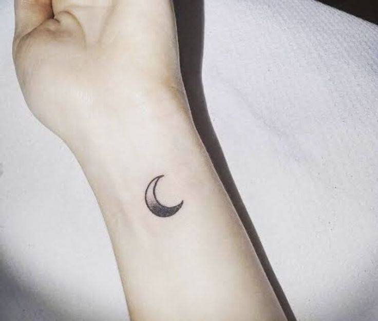 a woman's arm with a small crescent tattoo on the left side of her wrist