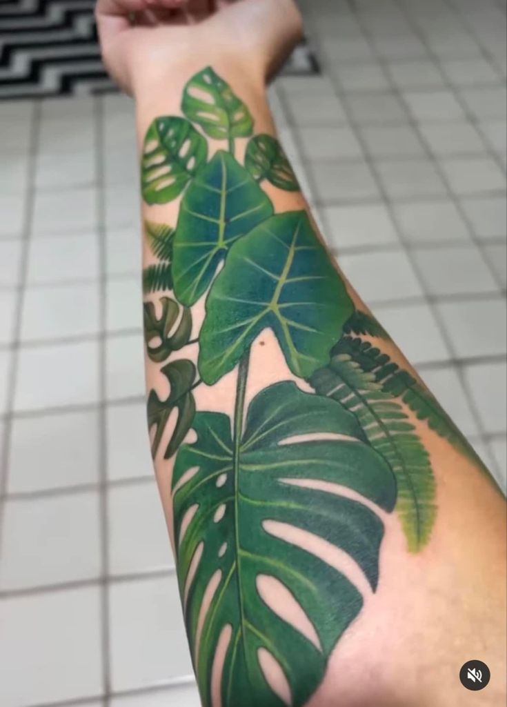 a person with a green leaf tattoo on their arm