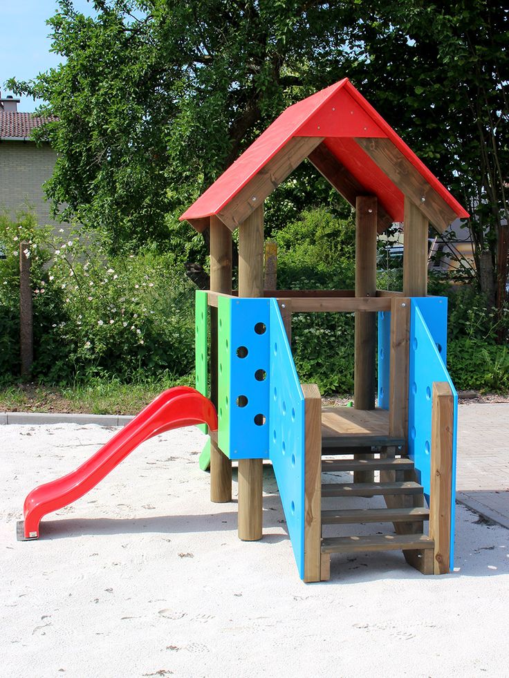 a wooden play structure with slide and climbing frame in the sand at a playground area