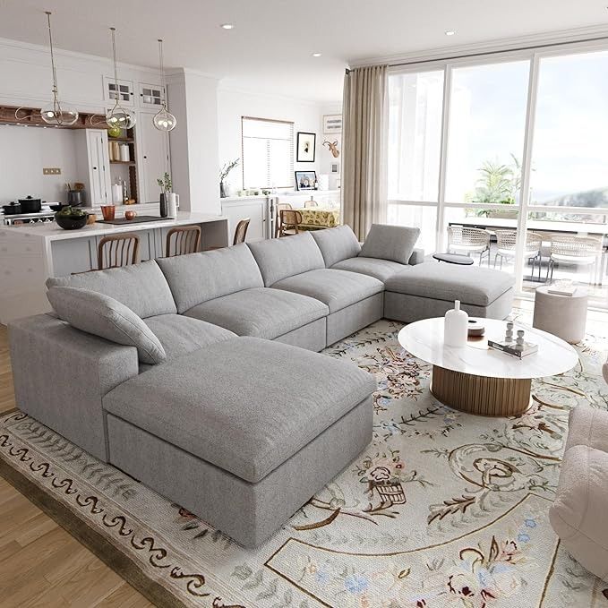 a living room filled with furniture next to a large open floor plan and lots of windows