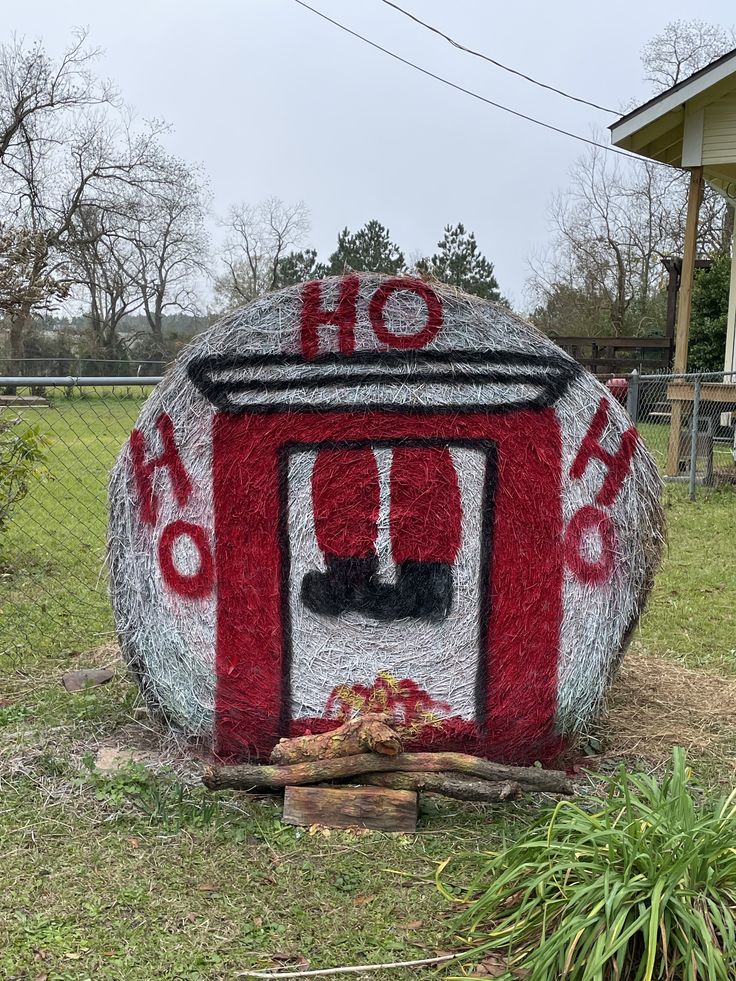 a red and white painted rock sitting on top of a grass covered field