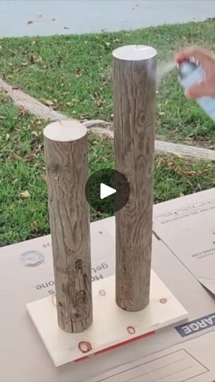 a person sprays water on two wooden posts in front of some mail and grass